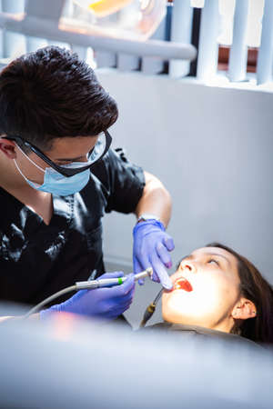 Series of photos at a dentist's office. A young brunette woman sitting in a dentist's chair. A dentist giving her a lip injectionの写真素材