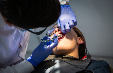 Close up of a young brunette woman sitting in a dentist's chair. A dentist giving her a lip injectionの写真素材