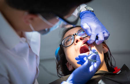 Series of photos at a dentist's office. A young brunette woman sitting in a dentist's chair. A dentist giving her a lip injectionの写真素材