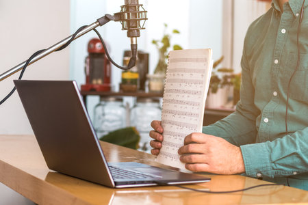 Close up of a young man sitting at the table with laptop. He has a microphone, he's teaching live...