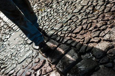 Close up of male legs walking on the cobblestone road.の写真素材