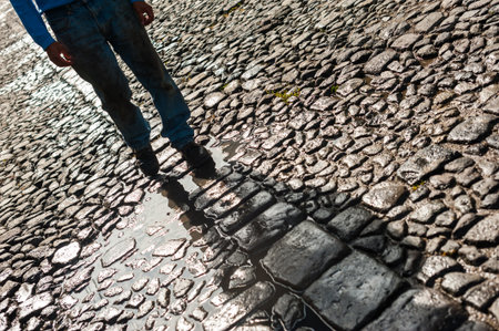 Close up of man walking on cobblestone road in city.の写真素材