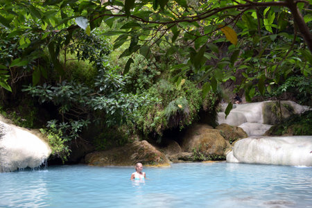 A girl dipping herself in a blue-torquoise pool in Erawan National Park, Kanchanaburi, Thailand.のeditorial素材