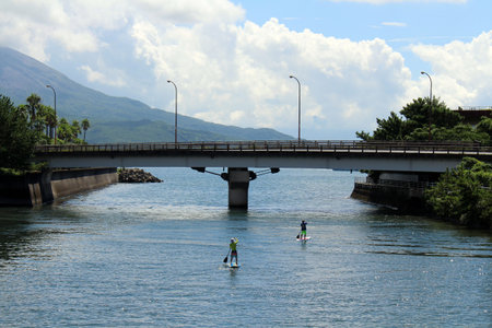 People paddling under the bridge overlooking Sakurajima of Kagoshima.