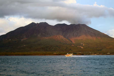 Closeup view of ferry passing by Sakurajima during sunset. Taken in August 2019.の写真素材