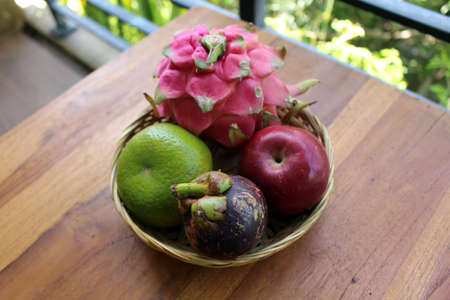 A bowl of Indonesian tropical fruits. Dragon fruit, mangosteen, apple, orange.の写真素材