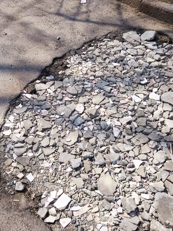A huge pit on the road filled by rubble.の写真素材