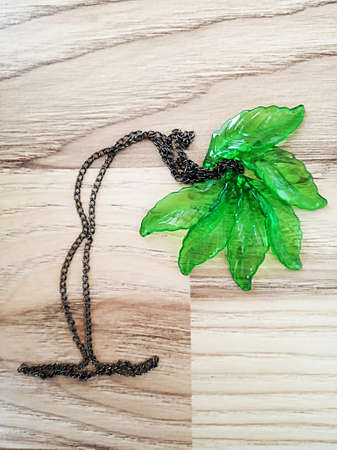 Decorative green glass leaves and chain composition on wooden pattern.の写真素材