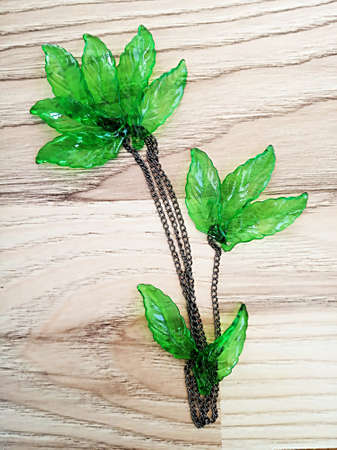 Decorative green glass leaves and chain composition on wooden pattern.の写真素材