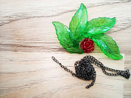 Decorative green glass leaves chain and rose composition on wooden pattern.の写真素材