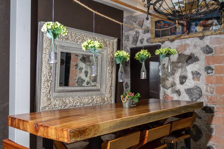 Designer bar stools at gray kitchen island with bottles under grey lamp in bright kitchen interior with binの写真素材