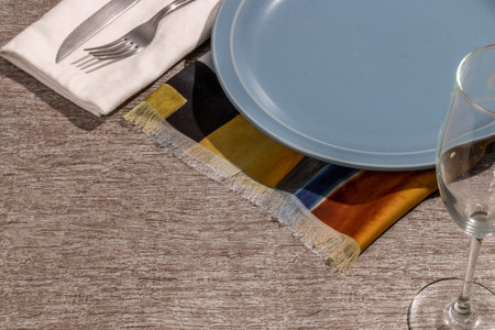 plate, cutlery wine glass and colored napkin on gray toned surface