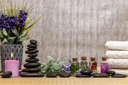 Composition of spa treatment, candles in bowl with water. Bottles of essential oil with dried rose...
