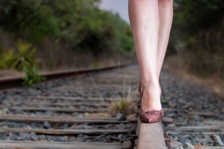 Detail of legs of a real woman walking on the railroad track, with heels, yellow dress and hat. Summer afternoonの写真素材