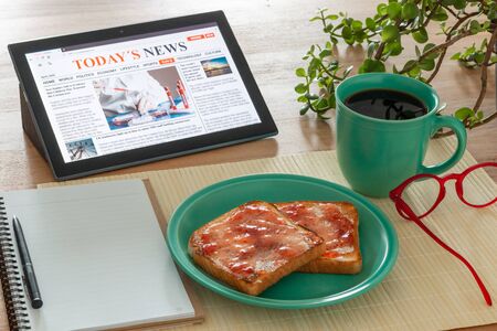 Breakfast table with bread and coffee reading the today's newsの写真素材