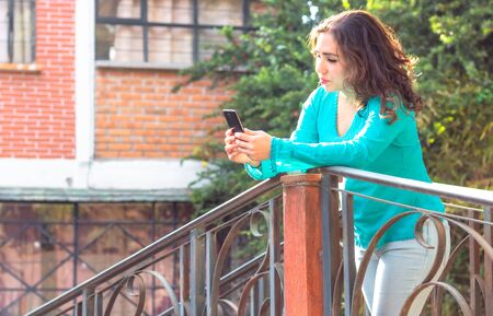 Woman using smartphone in the field. Real girl surfing the Internet with phone, texting and communicating outdoors. Travel conceptの写真素材