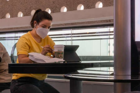 Real woman working on tablet with face mask. New normalのeditorial素材
