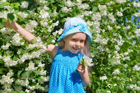 Little funny girl with blooming jasmine bush の写真素材