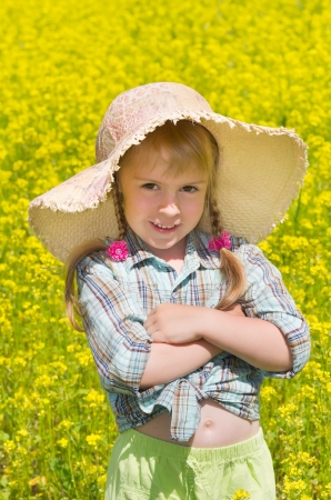 The little girl in the hat among the blossoming of the field.の写真素材