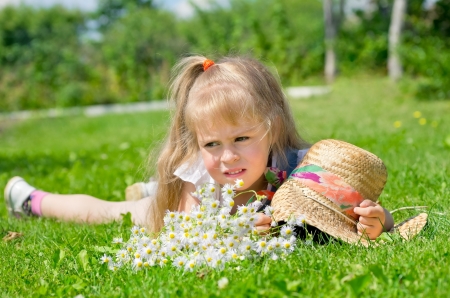 The thoughtful little girl lies on a lawnの写真素材