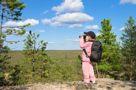 Little girl looking through binoculars from a high mountainの写真素材