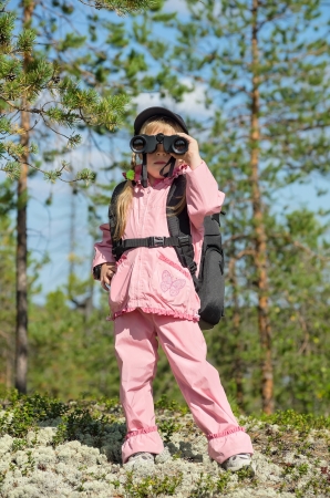 Little girl in a forest looking through binocularsの写真素材