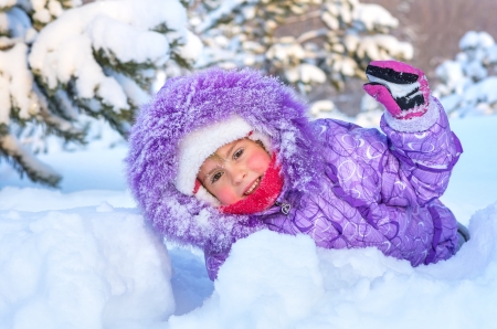 Cheerful little girl playing in a snowy forest  On the face of snowflakes and a drop of water from melting snow の写真素材