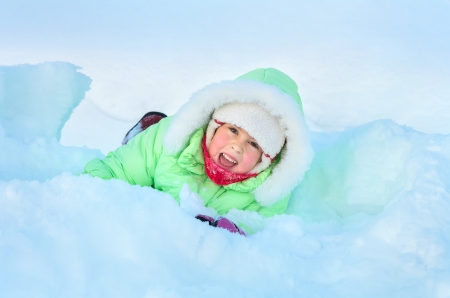 Cheerful girl lying in deep snow driftの写真素材