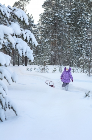 Little girl walking in winter forestの写真素材