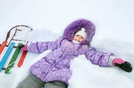 Little girl lying in deep snowの写真素材