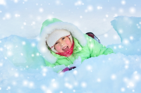 Cheerful girl lying in deep snow driftの写真素材
