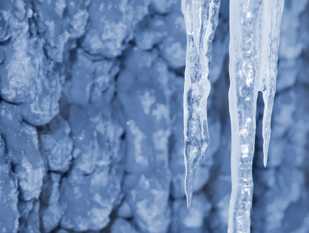 Hanging transparent icicles on background of wallの写真素材