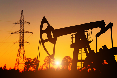 Oil pump against background of dawn and high-voltage pylonの写真素材