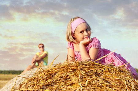 Family mom with cheerful daughter in the field.
Cheerful child on straw rolls.の写真素材