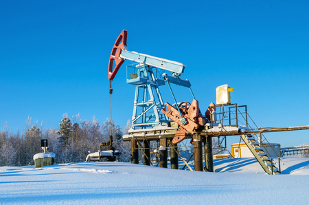 Oil field. Winter landscape with an oil pump in the rays of the setting sun.の写真素材