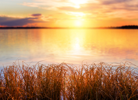 Natural blurred background. Autumn landscape with grass on the bank of the lake and  colourful declineの写真素材