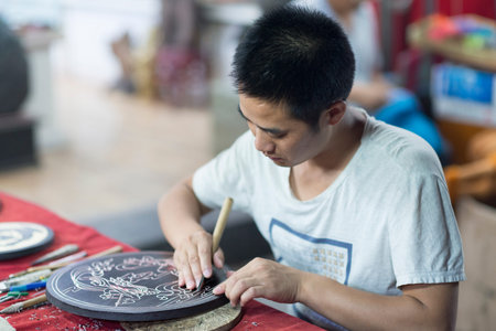 Dunhuang, China - 08 06 2016: A craftsman depicts Dunhuang culture through wood carvings. Chinese...