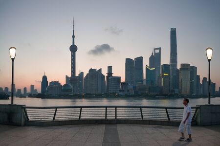 Shanghai, China - 08 27 2016: Chinese people enjoy walking or running at The Bund early in the morning at sunrise. View of Pudong from The Bund in Shanghai, Chinaのeditorial素材