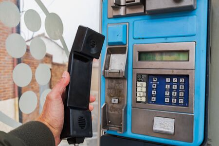 old and dirty blue telephone cabin without maintenance and still working in a small town in Spainの写真素材