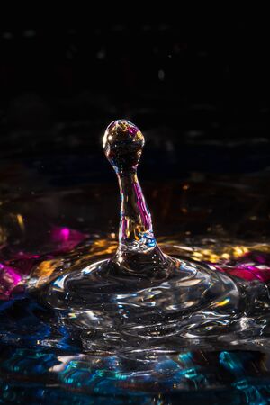water drops splash forming ripples and waves and abstract water columns in a colorful backgroundの写真素材