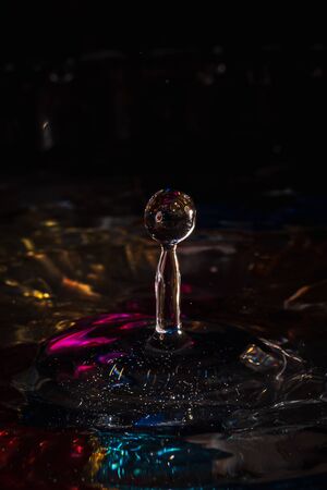 water drops splash forming ripples and waves and abstract water columns in a colorful backgroundの写真素材