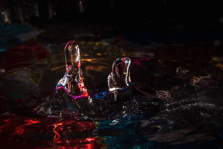 water drops splash forming ripples and waves and abstract water columns in a colorful backgroundの写真素材