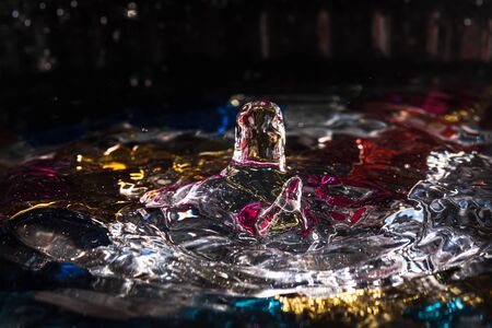 water drops splash forming ripples and waves and abstract water columns in a colorful backgroundの写真素材