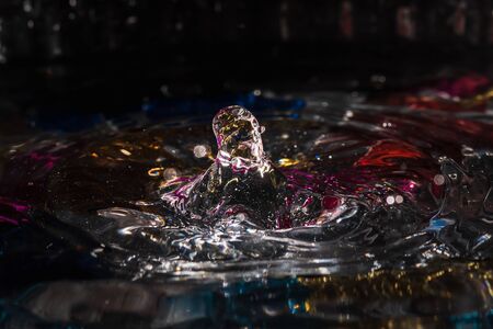 water drops splash forming ripples and waves and abstract water columns in a colorful backgroundの写真素材