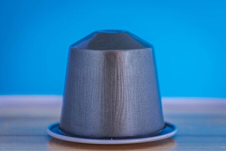 closeup lateral view of an aromatic, tasty espresso gray coffee capsule with light blue backgroundのeditorial素材