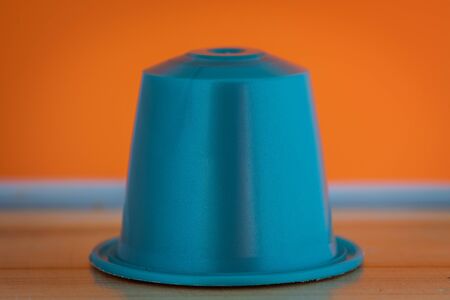 closeup lateral view of an aromatic, tasty espresso light blue coffee capsule with orange backgroundのeditorial素材
