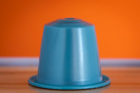 closeup lateral view of an aromatic, tasty espresso light blue coffee capsule with orange backgroundのeditorial素材