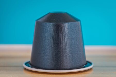 closeup lateral view of an aromatic, tasty espresso blue coffee capsule with light blue backgroundのeditorial素材