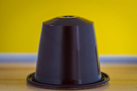 closeup lateral view of an aromatic, tasty espresso brown coffee capsule with yellow backgroundのeditorial素材