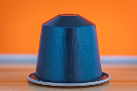 closeup lateral view of an aromatic, tasty espresso dark blue coffee capsule with orange backgroundのeditorial素材